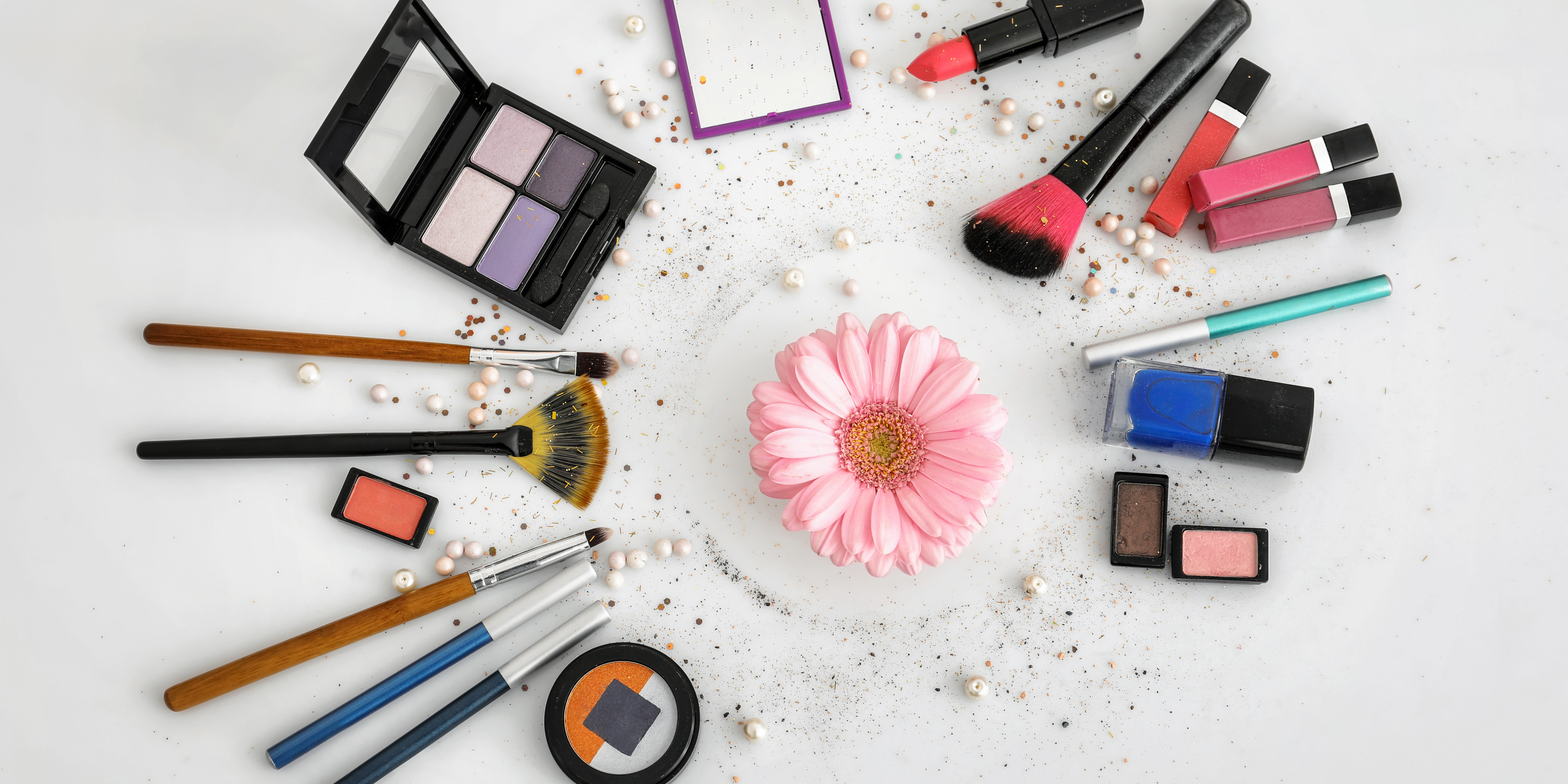 various makeup product flat lay light background with pink flower in center